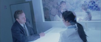 Movie still from “Code 46” (2003), directed by Michael Winterbottom – A man and a woman are sitting in front of a mirror; Medium shot, Over the shoulder angle