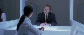 Movie still from “Code 46” (2003), directed by Michael Winterbottom – A man and a woman sitting at a table talking to each other; Medium shot, Low angle