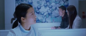 Movie still from “Code 46” (2003), directed by Michael Winterbottom – A woman and a boy in a room with a blue wall; Medium shot, Over the shoulder angle