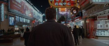 Movie still from “Code 46” (2003), directed by Michael Winterbottom – A man is walking down the street at night; Medium shot, Low angle