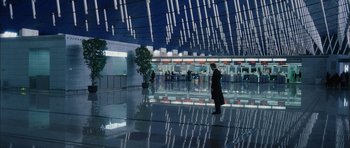 Movie still from “Code 46” (2003), directed by Michael Winterbottom – A man in a black suit is walking through a building; Extreme Wide shot, High angle