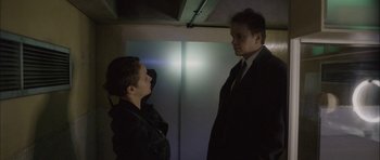 Movie still from “Code 46” (2003), directed by Michael Winterbottom – Two men in suits talking to each other in the dark; Medium shot, Low angle