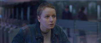 Movie still from “Code 46” (2003), directed by Michael Winterbottom – A woman with short hair is looking into the distance; Close Up shot, High angle
