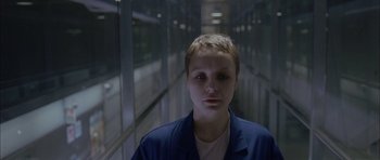 Movie still from “Code 46” (2003), directed by Michael Winterbottom – A man with short hair is standing in a hallway; Close Up shot, High angle