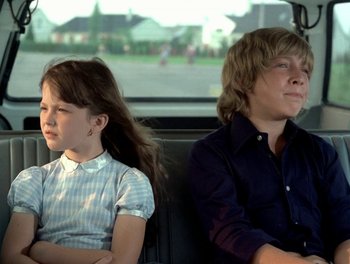 Movie still from “Cousin cousine” (1975), directed by Jean-Charles Tacchella – Two people sitting in the back seat of a car; Medium shot, Low angle