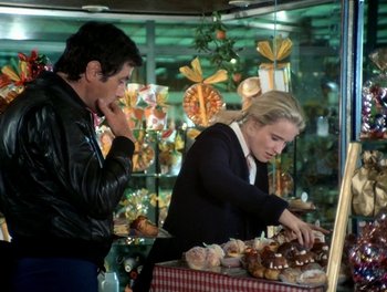 Movie still from “Cousin cousine” (1975), directed by Jean-Charles Tacchella – A man and a woman looking at a display of baked goods; Medium shot, Over the shoulder angle