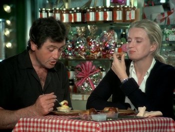 Movie still from “Cousin cousine” (1975), directed by Jean-Charles Tacchella – A man and a woman sitting at a table eating cake; Medium shot, High angle