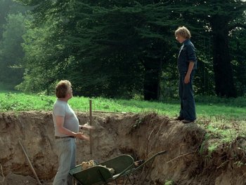 Movie still from “Cousin cousine” (1975), directed by Jean-Charles Tacchella – Two people standing on the side of a dirt road; Wide shot, High angle