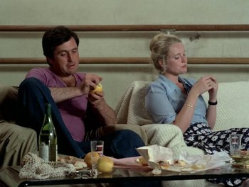 Movie still from “Cousin cousine” (1975), directed by Jean-Charles Tacchella – A man and a woman sitting next to each other on a couch; Medium shot, Low angle