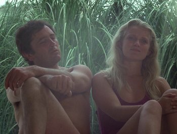 Movie still from “Cousin cousine” (1975), directed by Jean-Charles Tacchella – A man and a woman sitting next to each other in the grass; Medium shot, Low angle