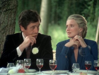 Movie still from “Cousin cousine” (1975), directed by Jean-Charles Tacchella – A man and a woman sitting next to each other at a table; Medium shot, Over the shoulder angle