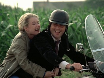 Movie still from “Cousin cousine” (1975), directed by Jean-Charles Tacchella – A man and a woman riding a motorcycle together; Medium shot, High angle