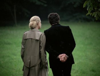 Movie still from “Cousin cousine” (1975), directed by Jean-Charles Tacchella – A man and a woman holding hands while standing in the grass; Medium shot, Over the shoulder angle
