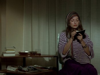 Movie still from “Cousin cousine” (1975), directed by Jean-Charles Tacchella – A woman sitting on a chair looking at her cell phone; Medium shot, High angle