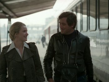Movie still from “Cousin cousine” (1975), directed by Jean-Charles Tacchella – A man and a woman walking on a train platform next to each other; Medium shot, Over the shoulder angle