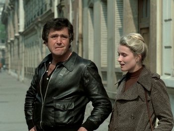 Movie still from “Cousin cousine” (1975), directed by Jean-Charles Tacchella – A man and a woman standing next to each other on the street; Medium shot, Over the shoulder angle