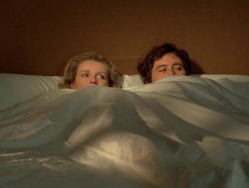 Movie still from “Cousin cousine” (1975), directed by Jean-Charles Tacchella – A couple of people that are under a blanket; Medium shot, Overhead angle