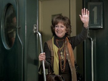 Movie still from “Cousin cousine” (1975), directed by Jean-Charles Tacchella – A woman waves to the camera while riding a bus; Medium shot, Over the shoulder angle