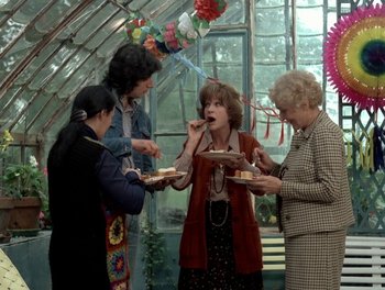 Movie still from “Cousin cousine” (1975), directed by Jean-Charles Tacchella – A group of people standing around eating cake; Medium shot, Over the shoulder angle