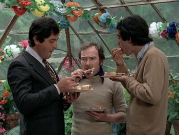 Movie still from “Cousin cousine” (1975), directed by Jean-Charles Tacchella – A group of men standing next to each other eating food; Medium shot, Over the shoulder angle