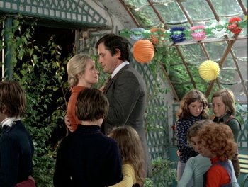 Movie still from “Cousin cousine” (1975), directed by Jean-Charles Tacchella – A man and a woman standing next to each other in front of a group of children; Medium shot, High angle