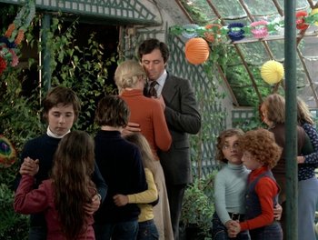 Movie still from “Cousin cousine” (1975), directed by Jean-Charles Tacchella – A group of people standing around each other in front of a building; Medium shot, High angle