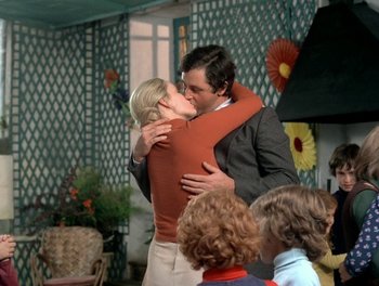 Movie still from “Cousin cousine” (1975), directed by Jean-Charles Tacchella – A man and a woman kissing each other in front of a group of children; Medium shot, Low angle