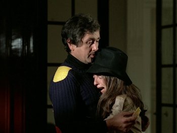 Movie still from “Cousin cousine” (1975), directed by Jean-Charles Tacchella – A man and a woman embracing each other in a dark room; Medium shot, Over the shoulder angle