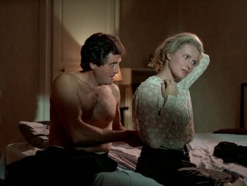 Movie still from “Cousin cousine” (1975), directed by Jean-Charles Tacchella – A man and a woman sitting on top of a bed; Medium shot, Low angle