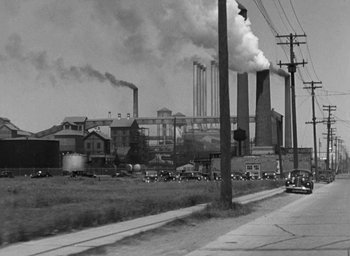 Movie still from “Dodsworth” (1936), directed by William Wyler – An old photo of an industrial area with smoke coming out of the chimney; Extreme Wide shot, Low angle