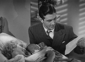 Movie still from “Dodsworth” (1936), directed by William Wyler – An old photo of a man and a woman holding a baby; Medium shot, High angle