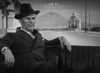 Movie still from “Dodsworth” (1936), directed by William Wyler – An older man sitting on a bench in front of a mountain; Medium shot, Low angle