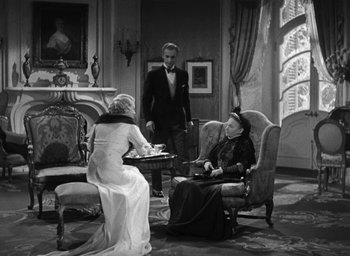 Movie still from “Dodsworth” (1936), directed by William Wyler – An old photo of two women and a man in a living room; Wide shot, High angle