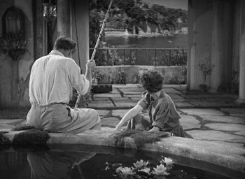 Movie still from “Dodsworth” (1936), directed by William Wyler – A man and a woman sitting next to each other on the ground; Wide shot, High angle