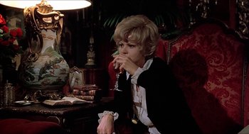 Movie still from “Family Plot” (1976), directed by Alfred Hitchcock – A woman sitting at a table drinking a glass of wine; Medium shot, Low angle