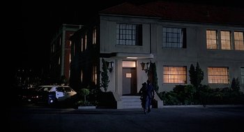 Movie still from “Family Plot” (1976), directed by Alfred Hitchcock – Two people walking down the street in front of a building; Extreme Wide shot, Low angle