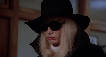 Movie still from “Family Plot” (1976), directed by Alfred Hitchcock – A woman wearing sunglasses and a black hat; Close Up shot, Low angle
