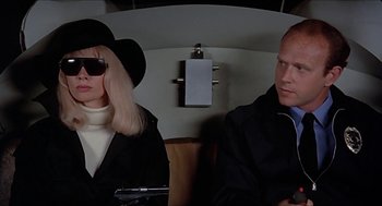 Movie still from “Family Plot” (1976), directed by Alfred Hitchcock – A man and a woman sitting next to each other on a train; Close Up shot, Over the shoulder angle