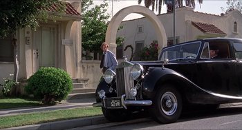 Movie still from “Family Plot” (1976), directed by Alfred Hitchcock – A man standing in front of an antique car; Wide shot, Low angle