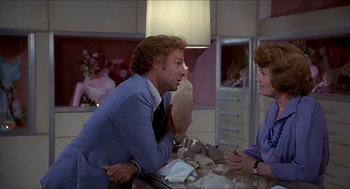 Movie still from “Family Plot” (1976), directed by Alfred Hitchcock – A man and a woman sitting at a table in a room; Medium shot, Over the shoulder angle