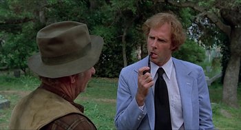 Movie still from “Family Plot” (1976), directed by Alfred Hitchcock – A man talking to another man while holding a cell phone to his ear; Close Up shot, Over the shoulder angle