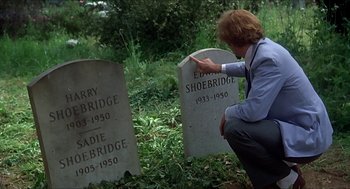 Movie still from “Family Plot” (1976), directed by Alfred Hitchcock – A person touching a headstone in a cemetery; Close Up shot, High angle