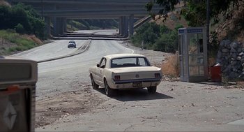 Movie still from “Family Plot” (1976), directed by Alfred Hitchcock – An old car is parked on the side of the road; Wide shot, High angle
