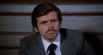 Movie still from “Family Plot” (1976), directed by Alfred Hitchcock – A man with a mustache in a suit; Close Up shot, Low angle