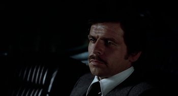 Movie still from “Family Plot” (1976), directed by Alfred Hitchcock – A person wearing a suit and tie; Close Up shot, Low angle