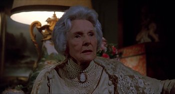 Movie still from “Family Plot” (1976), directed by Alfred Hitchcock – An older woman wearing a white dress and a necklace; Close Up shot, Low angle
