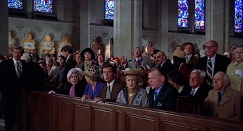 Movie still from “Family Plot” (1976), directed by Alfred Hitchcock – A group of people sitting in a church pews; Wide shot, High angle