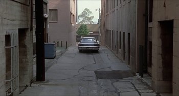 Movie still from “Family Plot” (1976), directed by Alfred Hitchcock – A car is parked in the middle of an alley way; Extreme Wide shot, High angle