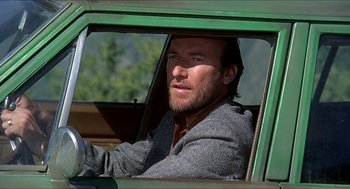 Movie still from “Family Plot” (1976), directed by Alfred Hitchcock – A man sitting in the driver's seat of a green car; Close Up shot, Low angle