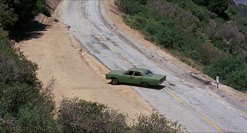 Movie still from “Family Plot” (1976), directed by Alfred Hitchcock – An old green car driving down a dirt road near a forest; Extreme Wide shot, High angle